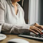 Executive assistant typing on a laptop with coffee